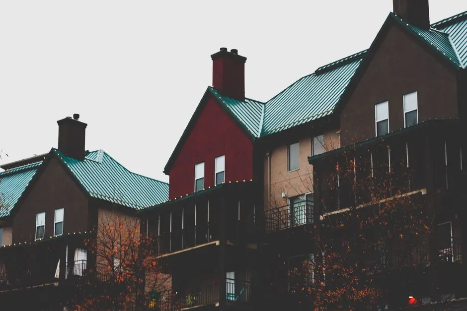 Modern urban apartment buildings with distinctive teal metal roofs and balconies.