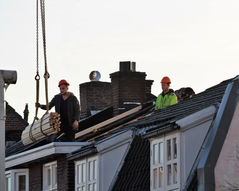 Workers operate on a rooftop under construction in the Netherlands, showcasing teamwork and safety.